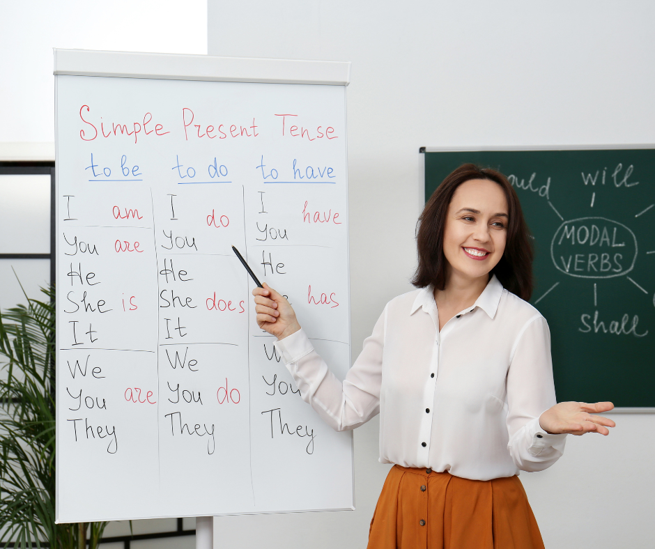 Profesoară zâmbitoare predând engleza de bază adulților la ILSE, demonstrând pasiunea pentru învățare și dezvoltare personală.